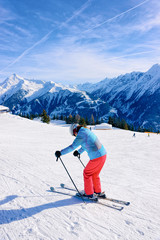 Fototapeta na wymiar Woman Skier skiing on Penken Park ski resort in Tyrol in Mayrhofen in Zillertal valley in Austria in winter Alps. Girl ski Alpine mountains with white snow and blue sky. Austrian snowy slopes.