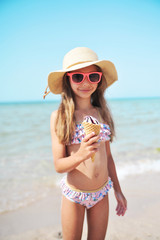 Cute little girl has fun on the beach. Summertime concept.