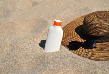 Hat and sun cream protection on sand, Summer time concept.