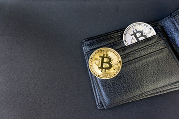 Metal bitcoins in black leather wallet. Profit from mining crypto currencies. Miner with dollars and gold bitcoin.
