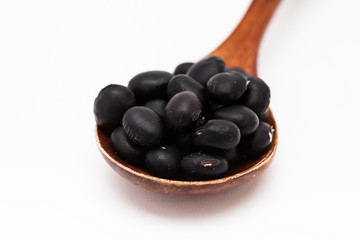 Black bean grains spoon on a white