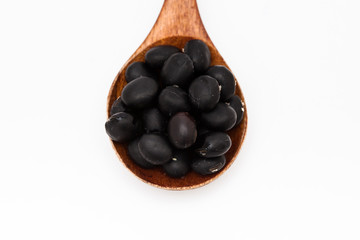 Black bean grains spoon on a white