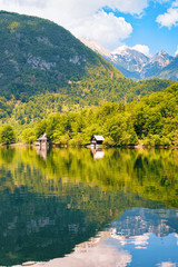 Scenery of wooden houses at Bohinj Lake in Slovenia. Nature in Slovenija. View of Beautiful landscape and blue sky in summer. Alpine Travel destination. Julian Alps mountains on scenic background