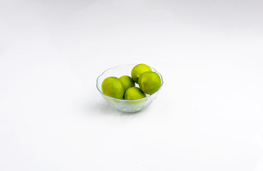 Green lemon on a glass bowl in white background