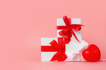 Romantic gifts present wrapped and decorated with bow on pink background with copy space. Gift for mother's day, valentine's day, birthday, wedding day.