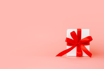 Romantic gifts present wrapped and decorated with bow on pink background with copy space. Gift for mother's day, valentine's day, birthday, wedding day.