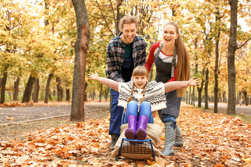 Family having fun while cleaning up autumn leaves outdoors