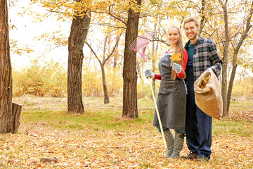 Couple cleaning up autumn leaves outdoors