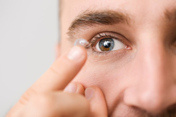 Young man putting in contact lenses, closeup
