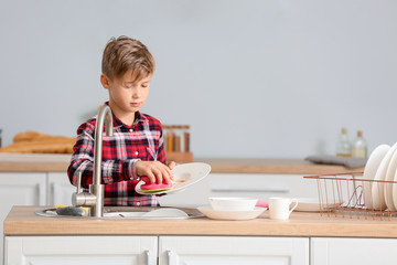 Fototapeta na wymiar Little boy washing dishes in kitchen