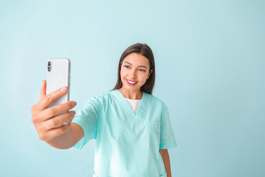 Young Nurse Taking Selfie On Color Background