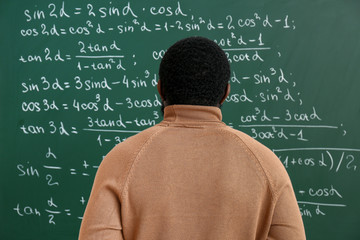 African-American math teacher near blackboard in classroom