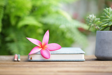 pink flower and book on wooden table at outdoor