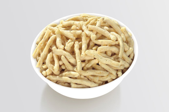 Bhavnagari Gathiya is a very popular Gujarati snack, white bowl on white background, pouch packing common street snack from India. selective focus - Image