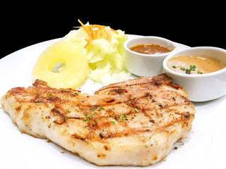 Closeup T-bone pork steak with fruit salad,  pepper and tomato sauce on white ceramic plate isolate on black background and make with paths.