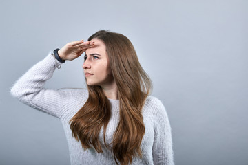 Focused caucasian brunette woman in denim blue shirt keeping palm at forehead, looking into...