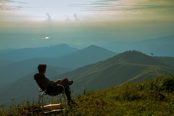 silhouette of man sitting on top of mountain