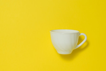 White ceramic coffee Cup on a yellow background.