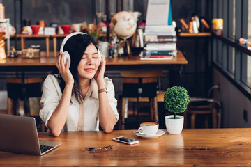 Lifestyle freelance woman he using earphones listening music during working on laptop computer