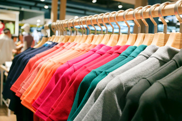 Close up men t-shirts on wooden hanger in in mall or clothing store.