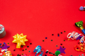 Festive golden and purple stars of confetti  and a present, birthday caps on a red background.