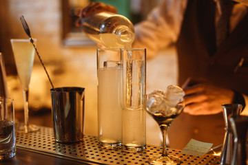 Bartender preparing a cocktail in a highball glass with crystal clear ice inside, at the bar...