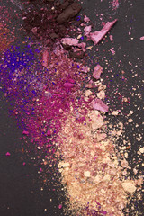 This is a photograph of nude,brown,blue,pink and purple matte and shimmery powder Eyeshadow on a Black background