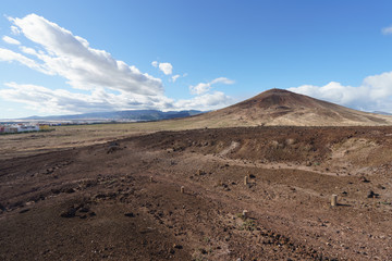 Gran Canaria summer landscape. Red ground. Blue high sky, mountin snd ehitr clouds. Holidays and touristic concepts.