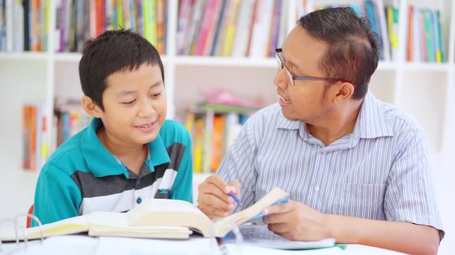 Young man helping his preteen son to study