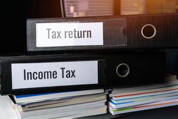 Tax return and Income tax files binder of report, document in office. completion of documentation that calculates entity’s income earned  of payable to government, organisations or potential taxpayers