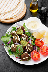 Vegetarian falafel with fresh green salad, sauce and lemon.
