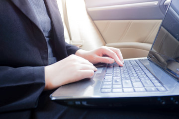 Cropped shot view of young businesswoman using laptop and smart phone  in a car.