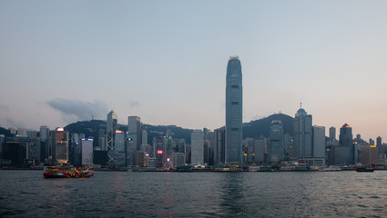 Skyline of Hong Kong Island at sunset across the Victoria Harbor, with a cruise sailing. 