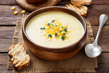 Delicious creamy sweetcorn soup served with toast and corn grains. - obrazy, fototapety, plakaty