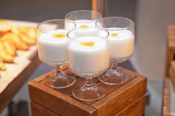 Breakfast at the hotel. Four cups of milk on a wooden table.