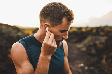 Man using wireless earphones air pods on running outdoors. Active lifestyle concept. - obrazy, fototapety, plakaty