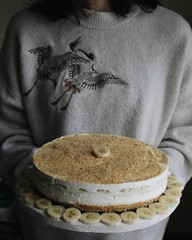 Female in a sweater holding a banana cheesecake, a moody image