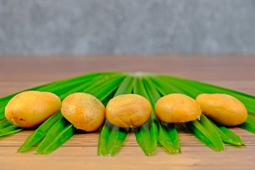 Ripen and ready-to-eat Salak, Zalacca on green leaf on wooden table with concrete as background.