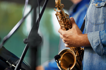 man holding a golden saxophone playing on it, musical instrument