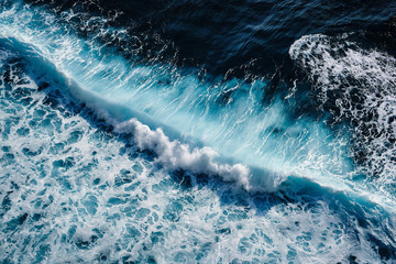 Aerial view to seething waves with foam. Waves of the sea meet each other during high tide and low tide. - obrazy, fototapety, plakaty