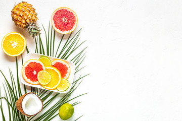 Tropical fruits and palm leaves on a white background.