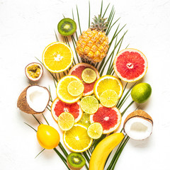 Tropical fruits and palm leaves on a white background.