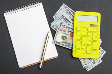 Notepad with calculator and money on the black background. Top view.