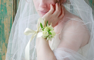 Bride wearing wrist corsage made of rose and eustoma flowers.