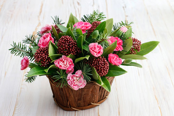 Woman shows how to make floral arrangement with carnations, skimmia (Skimmia japonica)