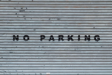  closed shutter on store or shop front saying no parking   -