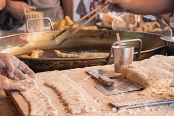 Chef cooking deep fried dough sticks - traditional thai street food dessert 