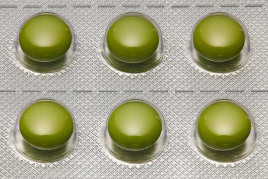 Green tablets in blister pack arranged with beautiful pattern. Global healthcare concept. Antibiotics drug resistance. Antimicrobial capsule pills. Pharmaceutical industry. Pharmacy.
