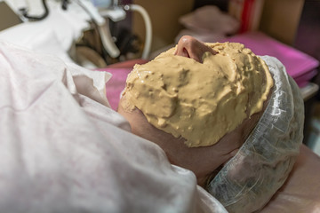 Cosmetic procedure with laying alginate masks on the face in a beauty salon. It is performed for an age woman. Improving skin turgor, rejuvenation and healing.