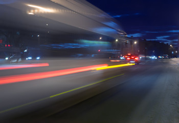 Naklejka premium bus driving along a night street in the winter in the city.